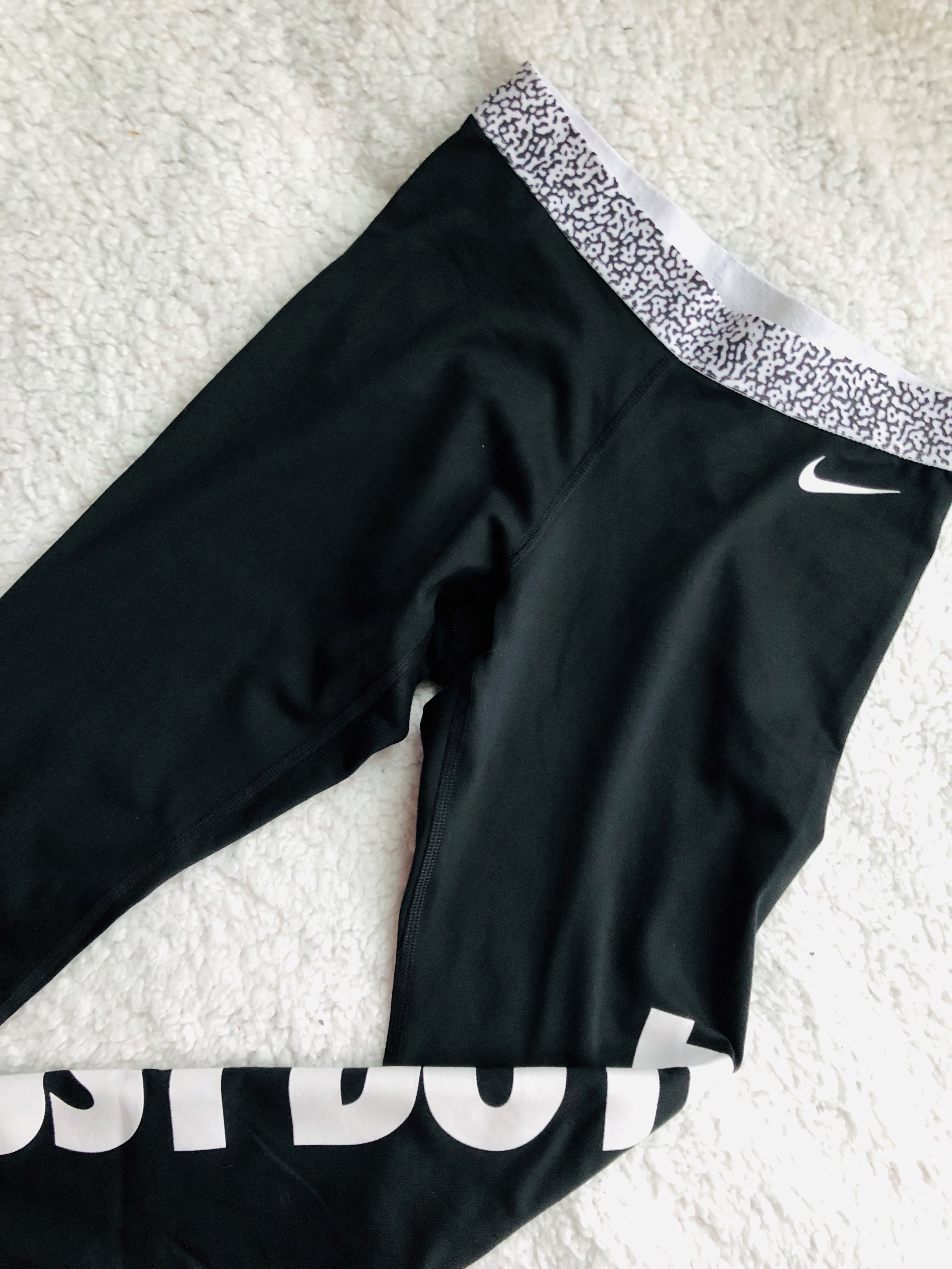 Black Nike sweatpants on a white bed.