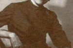 Black and white photo of a woman wearing a high-collared black dress and a wide-brimmed hat